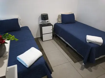 a room with two beds with blue sheets and a night stand at Apartamento centrico con vista exepcional al volcan de San Salvador in San Salvador
