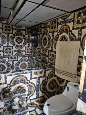 a bathroom with a toilet and a tiled wall at Alquileres El Ángel in San Salvador