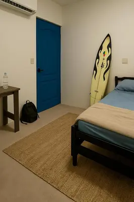 a bedroom with a blue door and a surfboard on the wall at The Duck Dive El Tunco in Tamanique