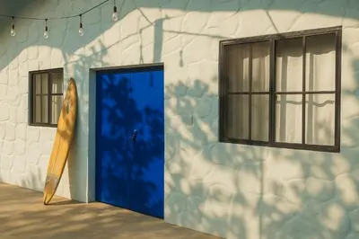 a blue door in front of a building with a surfboard at The Duck Dive El Tunco in Tamanique