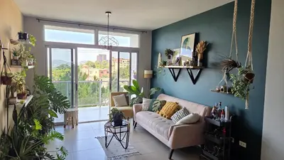a living room with a couch and a large window at Habitación en casa de Diana in San Salvador