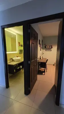 a hallway with a bathroom with a sink and a mirror at Habitación en casa de Diana in San Salvador
