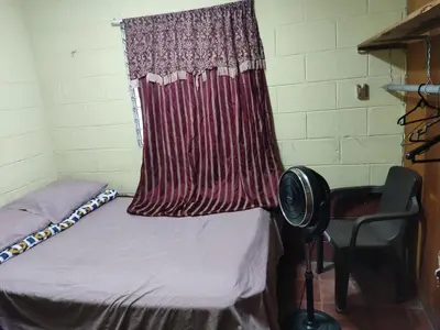 a room with a bed and a curtain and a chair at Kame-House Backpackers in San Salvador
