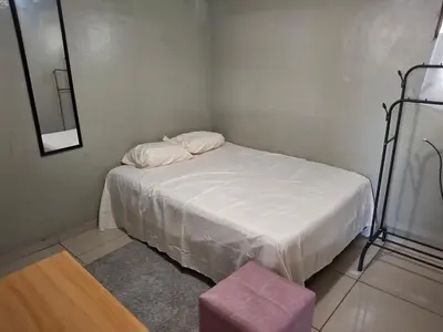 a small bedroom with a white bed with a pink stool at Apartamento in San Salvador