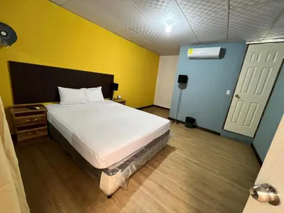 a bedroom with a white bed and a yellow wall at Casa de Huéspedes Noche de Luna in San Salvador