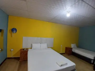 a bedroom with a white bed and a yellow wall at Casa de Huéspedes Noche de Luna in San Salvador