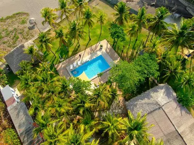 an overhead view of a swimming pool with palm trees at Mangomar Beach House in Teotepeque