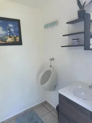 a white bathroom with a urinal on the wall at Mangomar Beach House in Teotepeque