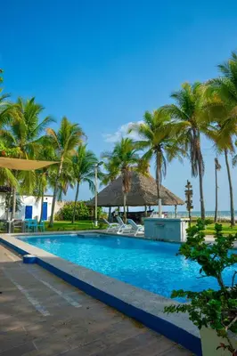 a swimming pool with palm trees and a beach at Mangomar Beach House in Teotepeque