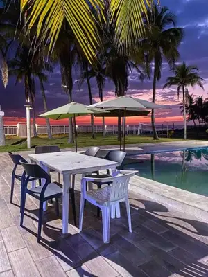 a table and chairs and umbrellas next to a pool at Mangomar Beach House in Teotepeque