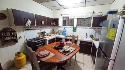 a kitchen with a wooden table and a refrigerator at Casa Flor Blanca in San Salvador