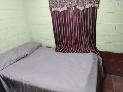 a bed in a room with a curtain on it at KameHouse Backpackers in San Salvador