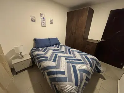 a bedroom with a bed with a blue and white comforter at Apartamento Nuevo ,Todo a tu alcance in San Salvador