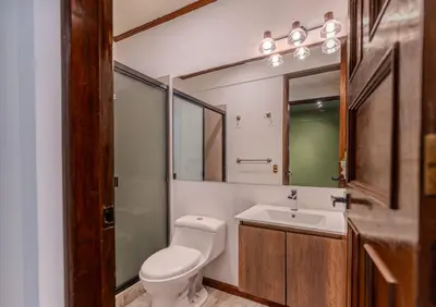 a bathroom with a toilet and a sink and a mirror at Casa Lúmina - Hotel Boutique, San Benito in San Salvador