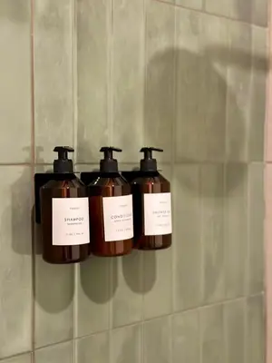 three bottles of soap on a shelf on a wall at Casa Lúmina - Hotel Boutique, San Benito in San Salvador