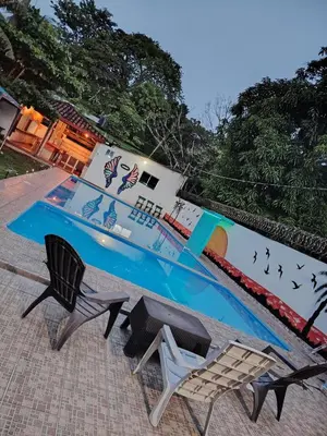 a swimming pool with two chairs and a table at Rancho Los Hernandez - Surf City - El Tunco in Tamanique