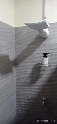 a person walking in a bathroom with a shower at Estancia WLC