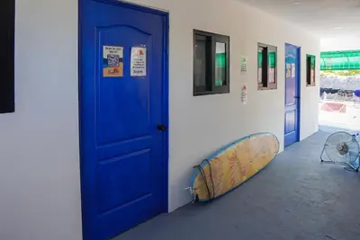 a room with a blue door and a surfboard on a wall at Surfside El Tunco in Tamanique