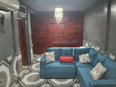 a living room with a blue couch with a red pillow at Mini apartamento familiar in San Salvador