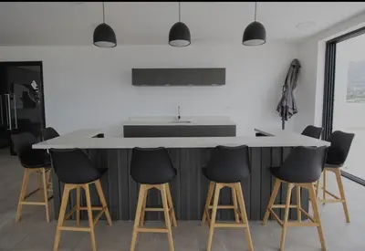 a kitchen with a white island with black counter stools at Un lugar especial en San Salvador in San Salvador