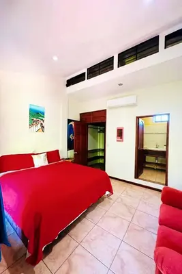 a bedroom with a red bed and a couch at Guazapa Cafe hotel petit in Suchitoto