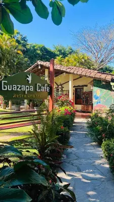 a sign in front of a building with flowers at Guazapa Cafe hotel petit in Suchitoto