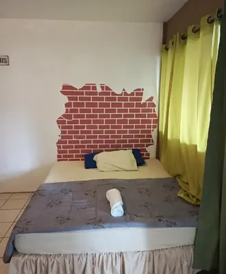 a bed in a room with a brick wall at Las Cabañitas, el boqueron in San Salvador