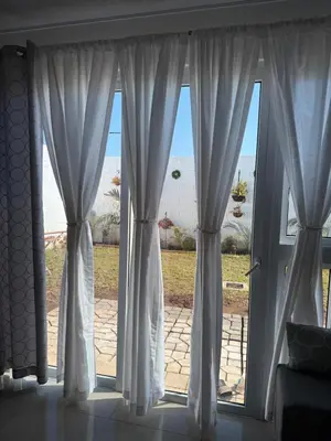 a window with white curtains and a view of the ocean at Elegante casa a minutos de Centro comercial in San Miguel