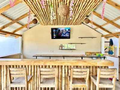 a bar with chairs and a tv on the ceiling at Sunzal Surf Garden - El Tunco in Tamanique
