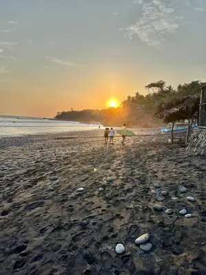 a group of people walking on the beach at sunset at Sunzal Surf Garden - El Tunco in Tamanique