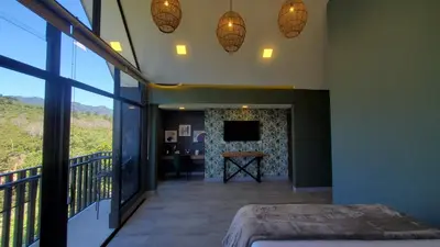 a bedroom with a balcony with a television and a table at Hotel Nido de Pájaro in Los Naranjos