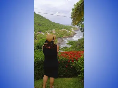 a woman in a black dress and hat looking at a river at Sueño del Pacifico in La Libertad