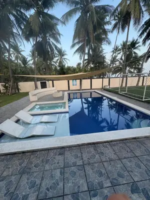 a swimming pool in a resort with palm trees at Rancho El Valle in Acajutla
