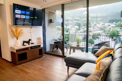 a living room with a couch and a large window at Apartment With Pool In Colonia Escalon in San Salvador