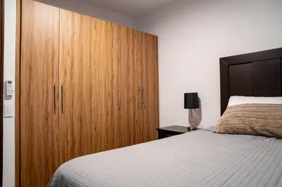 a bedroom with a large wooden cabinet next to a bed at Apartment With Pool In Colonia Escalon in San Salvador