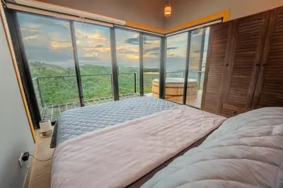 a bedroom with a bed in front of a large window at Dreamy cabin in Comasagua, La Libertad in Comasagua