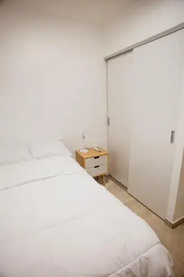a bedroom with a white bed and a wooden table at Apartment In The Greatest San Salvador in San Salvador