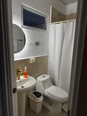 a bathroom with a toilet and a sink and a mirror at Golden House in San Miguel