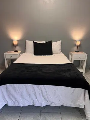 a bed with a black and white comforter and two side tables at Casa Victoria in San Miguel