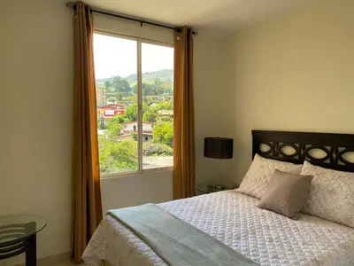 a bedroom with a bed and a large window at Beatiful Condo in Escalon near WTC building and Masferrer in San Salvador