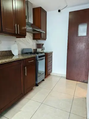 a kitchen with wooden cabinets and a stove at Habitaciones Privadas en Memories Flowershop - Colonia Escalón, Plaza Futura in San Salvador