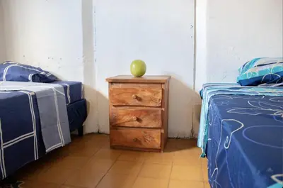 a room with two beds and a wooden dresser with an apple on it at Hostal Los Milagros in Santa Ana