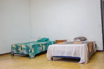 a room with two beds and a table in it at Hostal Los Milagros in Santa Ana