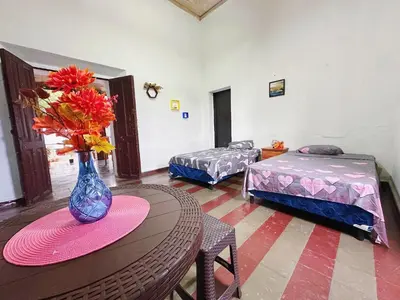 a room with a table with a vase with flowers on it at Hostal Los Milagros in Santa Ana