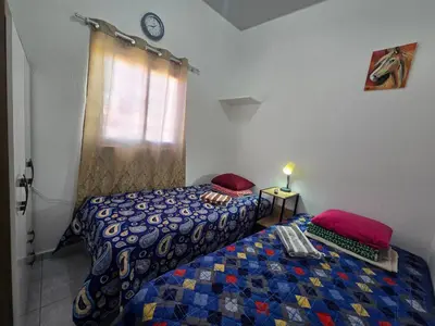 a bedroom with two beds and a clock on the wall at Casa en Villa Panamericana, San Miguel in San Miguel