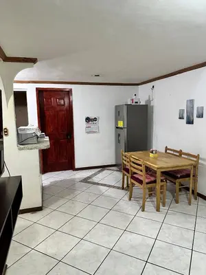 a kitchen with a wooden table and a refrigerator at Tu Estancia en San Salvador in Mexicanos