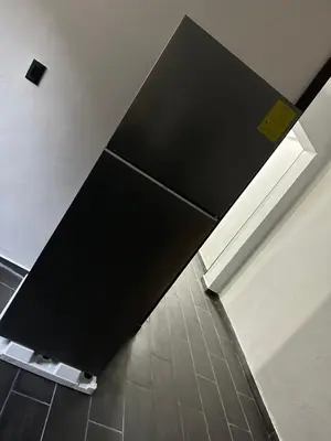 a black refrigerator in a room with a tile floor at Chavez in San Salvador