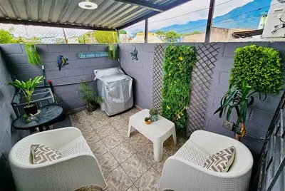 a patio with white chairs and plants and a wall at Cozy & Modern Condo In the Heart of San Salvador in San Salvador