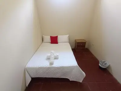a small room with a white bed with a red pillow at Casa Blanca el Zonte in El Zonte