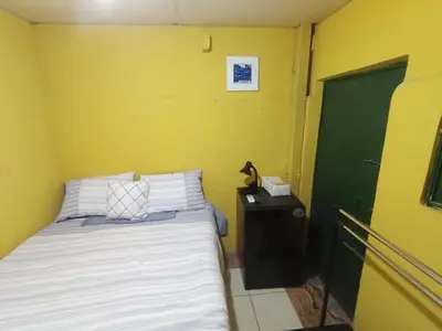 a small bedroom with a bed and a green door at Rooms libertad in San Salvador
